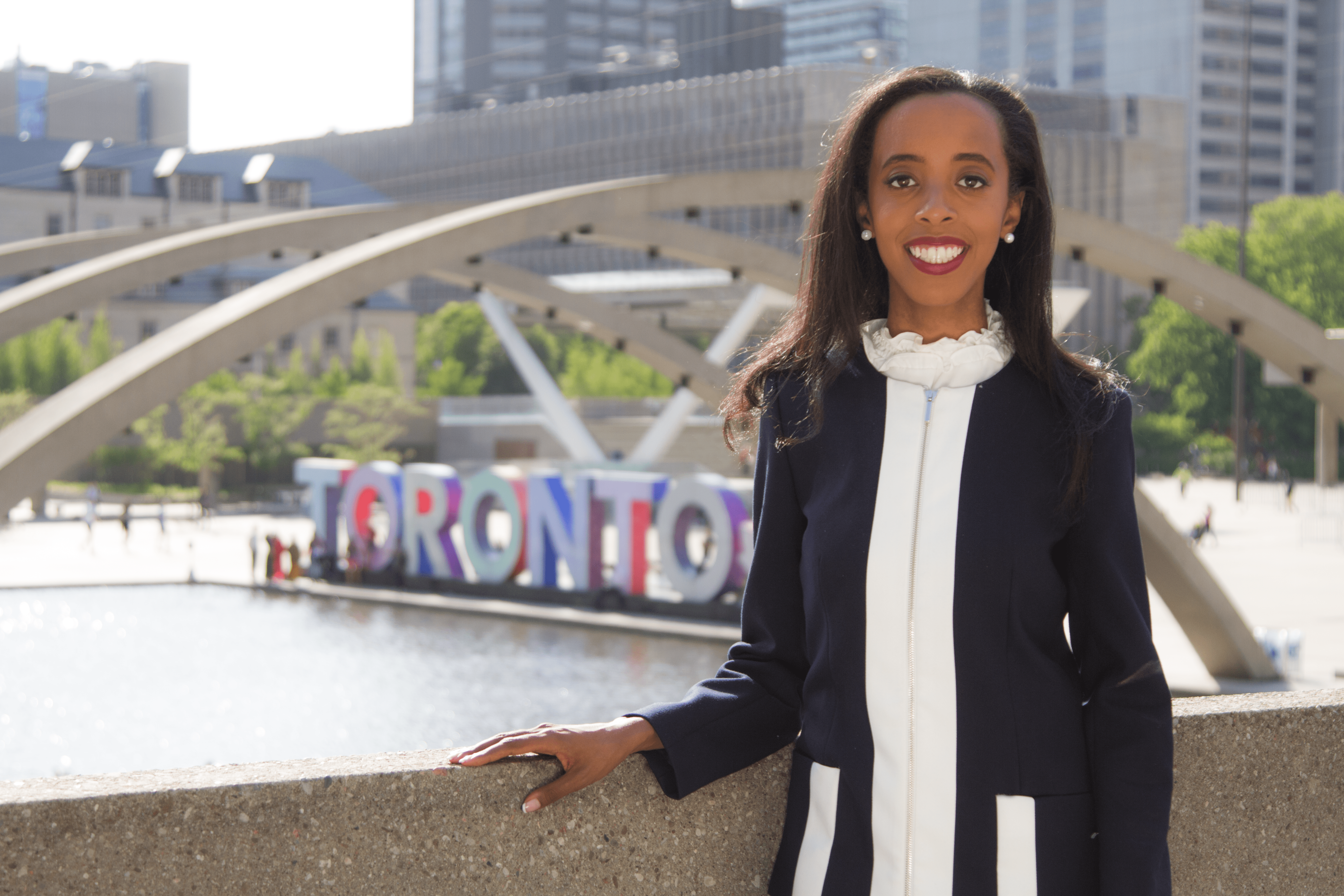A Picture of Saron Gebresellassi standing in front of the Toronto sign, in front of City Hall